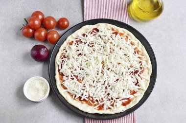 Rendelenmiş mozzarellayı pizzanın tabanına serp ve eşit bir şekilde dağıt..