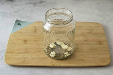 Soyulmuş sarımsak karanfilleri ve turşu turşusunu temiz, sterilize bir kavanozun dibine koy..