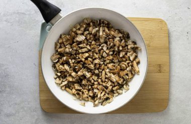 Şampiyonları da küp küp doğra, tavaya ekle ve fazla nem buharlaşana kadar kızart. Tuz ve biberli mevsim. Sonuna ince doğranmış yeşillikler ekle.