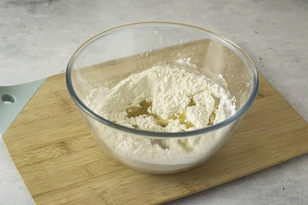 Unu derin bir kâseye koyun. Tuz ve sebze yağı ekle, karıştır. Hamuru kırıntılara çevir..