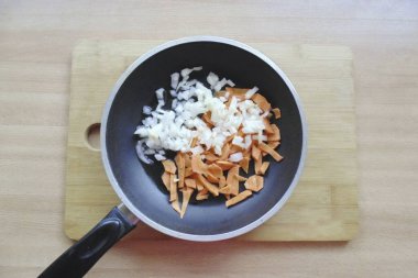 Soğan ve havuç soy ve yıka. Güzelce doğra ve sebze yağıyla bir tavaya koy..