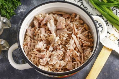 Sonra deriyi ve kıkırdağı çıkarın, eti liflere ayırın. Tuz, karabiber, birkaç tutam kırmızı biber ve soyulmuş sarımsak ezmesi ekle. Her şeyi iyice karıştır..