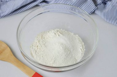 Şimdi pasta kalıbını hazırlaman gerek. Unu büyük bir kaseye koyun, şeker ve kabartma tozu ekleyin, karıştırın.