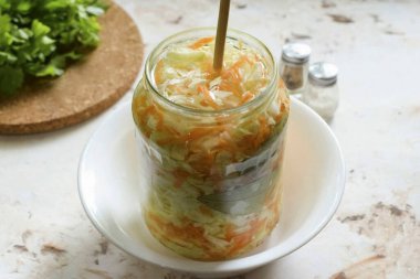 Derin bir kaseye bir kavanoz lahana koy, bir gün sonra, ahşap bir şiş ile düzenli olarak lahanayı delmeye başla..