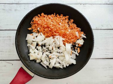 Soğanı soy ve güzelce doğra. Havuçları iyice yıka ve orta rende rendele. Sebzeleri iyi ısıtılmış sebze yağıyla tavaya koy ve 5-6 dakika kızart..