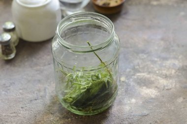 Kavanozu kabartma tozuyla iyice yıka, sonra da sıcak suyun altında durula. Kavanozu ve kapağı uygun bir şekilde sterilize et. Buhar yüzünden, fırında ya da mikrodalgada. Kavanozun altına yeşillik koy..