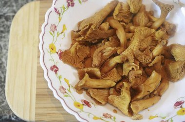 Kabaklı Chanterelles pişirmek için gerekli tüm malzemeleri hazırlayın. Chanterelleleri yıka. Donmuş mantarlarınız varsa, eritin ve sıvıyı sıkın..