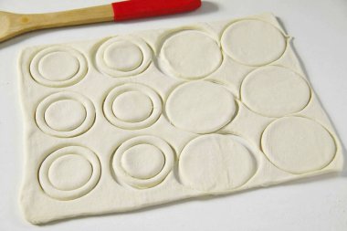 Hamuru 5-7 mm kalınlığında bir katman yap ve uygun cam veya camla daireler çiz. Çemberlerin yarısından halkaları kes. Çapı fotoğraftakinden biraz daha küçük..