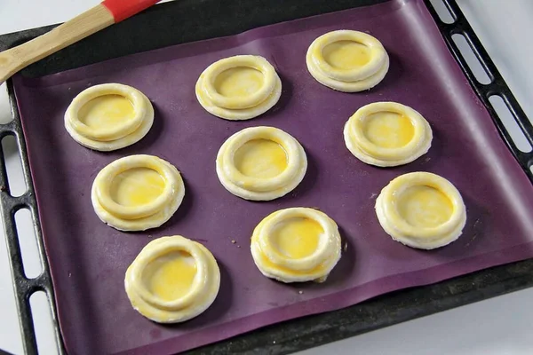 Combine the rest of the dough, roll out and cut out a few more batches. Fold the pieces one on top of the other and place them on a baking sheet lined with parchment or silicone mat. Brush with yolk.