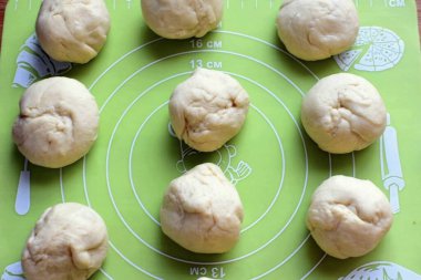 Hamuru tekrar diz ve orta büyüklükte bir yumurta büyüklüğünde parçalara böl. Topların içine yuvarlan ve biraz yükselt, plastikle kaplı olarak..