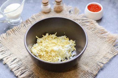 Tavuklu yumurtayı 10 dakika tuzlu suda kaynatın. Soğut ve yumurtayı soy, sonra da rendeleyip rendele. Rendelenmiş yumurtayı derin bir kaseye transfer et..