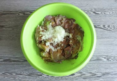 Soğanı kabaca rendele. Eti geniş bir kaseye aktarın, baharat, defne yaprağı ve rendelenmiş soğan ekleyin..