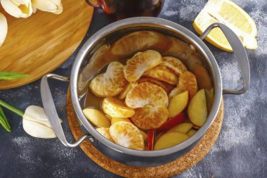 Yılbaşı şarabı yapmak için gerekli tüm malzemeleri hazırlayın. Elmaları suyla çalkala, çeyreklikleri kes ve tohum bloklarını kes. Tencere ya da kepçeyle dilimlenmiş. Mandalinayı soy ve altındaki beyaz tabakayı çıkar. Böl