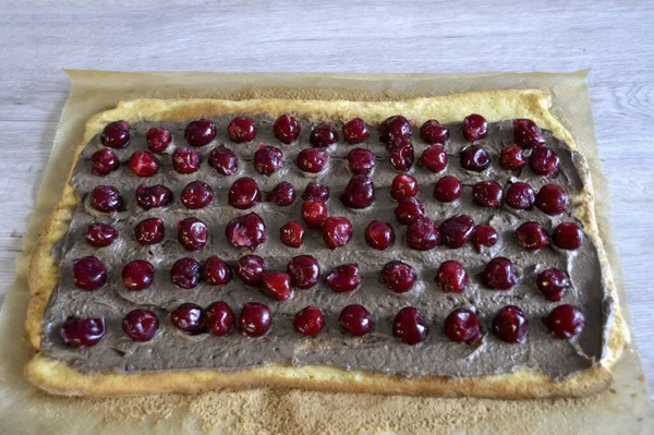 Lay out half of the cream, flatten, about 1.5-2 cm. Not reaching the edge of the crust, lay out the cherries. Roll seam down. It is advisable to place in the cold for half an hour to stabilize the roll.