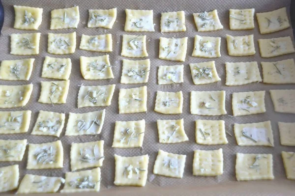 While the first batch of crackers is baking, roll out the second portion of the dough, sprinkle with rosemary and garlic.