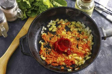 Havuç ve soğanları soy, suda durula, soğanı küçük küplere ayır ve fasulyeleri ince bir ızgara rendesinde rendele. Sebzeleri sebze yağında 3-4 dakika kadar kızartma tavasında tut, sonra da domates ezmesini ekle ve 1 dakika daha kızart.