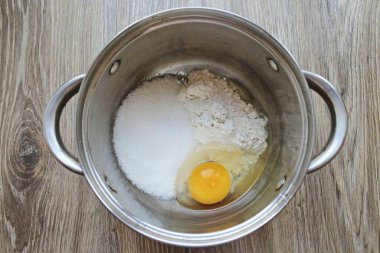 Krema için, unu ve şekeri tencereye koy. Onlara bir yumurta kır..