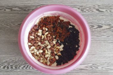 Kurutulmuş kayısıları ince şeritlere ayır, hamurla dolu bir kaseye transfer et. Kuru üzüm ve fındık ekle.