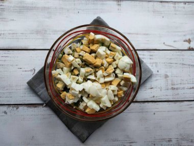 Haşlanmış yumurtaları soy, ince ince doğra ve diğer malzemelere ekle..