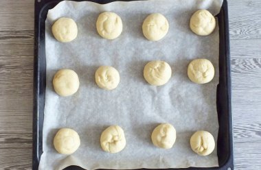 Kağıt parşömen kağıdıyla bir çarşaf doldur. Hamur toplarını yuvarlanan tarafa yerleştirin..