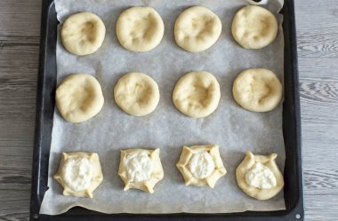 Her topu bardağın alt kısmıyla bastır. Sonra iş parçasının alt kısmına parmaklarınızla bastırın ve hafifçe kenarlara doğru gerin. Tanesi 0,5-1 tbsp. Dolgunun üstü olmadan. Kenarları viraj şeklinde tutturun. T