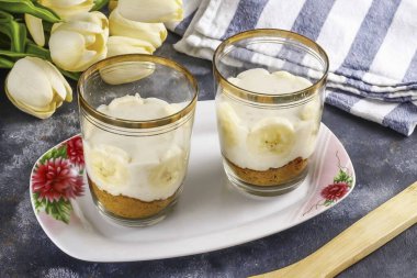 İkinci muzu soy, dilimlere böl, bir tanesini kremanın içine koy, bardaklardan ya da bardaklardan oluşan duvarların yanına, eğer şeffaflarsa..