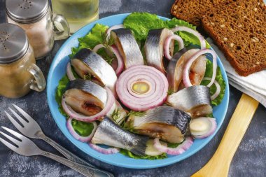 Tuzlu ringa balığını porsiyonlara ayırın ve tabağa koyun. Soyulmuş soğanı halkalara ayırın, balıklara ekleyin ve sebze yağı ekleyin. Masaya servis yap..