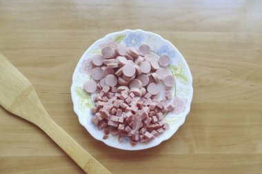 Sebzeler pişerken, sosise dön. Sosisleri ve yarısı tütsülenmiş sosisleri ince ince doğra..