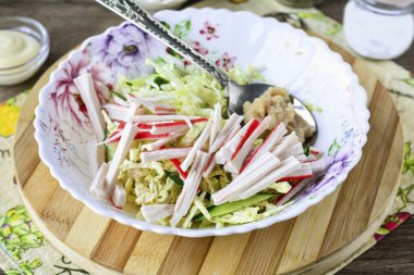 Şeritler halinde yengeç dilimleri kes ve salataya ekle. Ayrıca birkaç kaşık tuzlanmış kapelin yumurtası ekle..