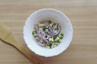 Kırmızı soğanı yarım halkalara ayır ve salataya ekle..