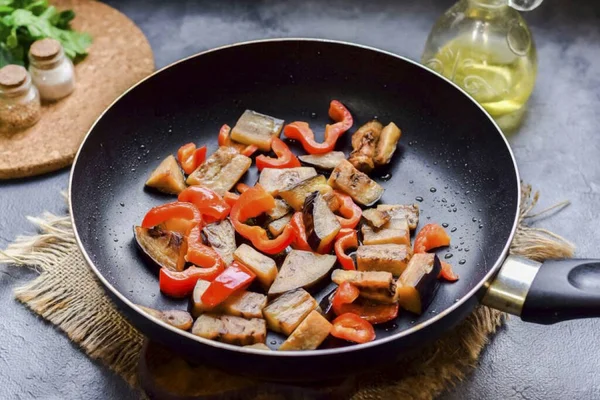 In a frying pan, warm vegetable oil, lay out peppers and eggplants. Fry vegetables, stirring, 3-4 minutes on medium fire.