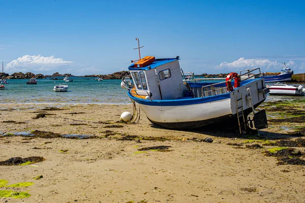 JP9_8912-Stranded boat Fishing boat on a beach in Brittany, France. Breton landscape in summer. A fishing boat stranded on the sand at low tide. Sand beach strewn with seaweed.