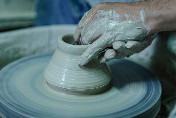 The hand of the potter in Betshdorf, France. Working on a potter's wheel preparing a vase. The grey clay of the Betschdorf region in Alsace is very well known.
