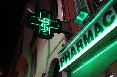 Pharmacy Neon Green Cross Sign at night  clipart