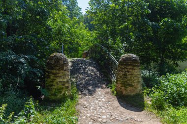 Yaz boyunca gölün yanındaki parkta eski bir taş köprü.
