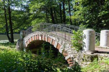 Yaz boyunca gölün yanındaki parkta eski bir taş köprü.