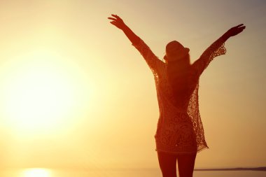 Taş, denizin üzerinde batımını ayakta genç kadın şapka ve sevimli yaz elbise