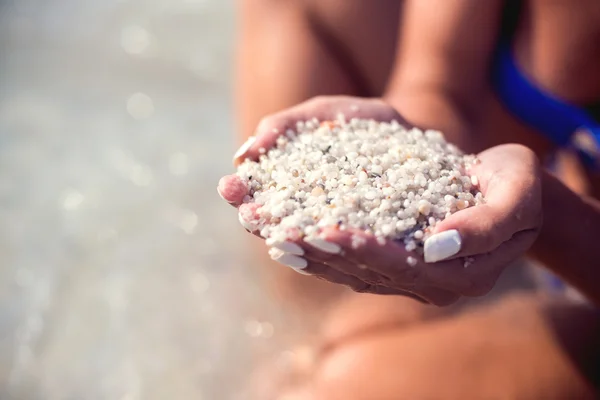 Flickorna händer som håller ovanligt sanden vid havet — Stockfoto