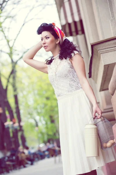 美しい女性が缶と卵のバスケットが付いている通りのポーズ. — ストック写真