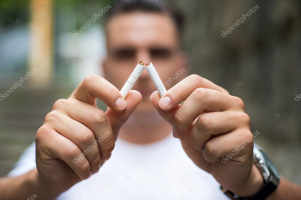 Young attractive man breaking cigarette