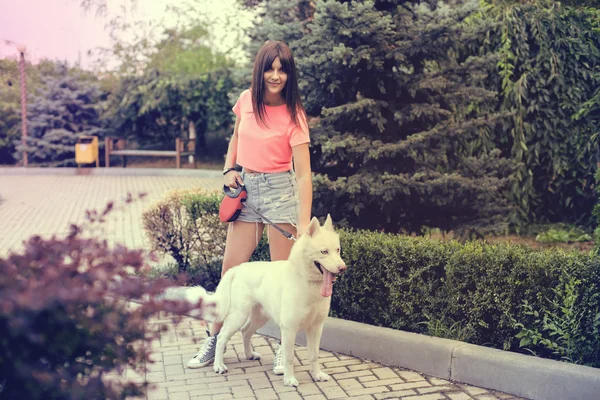 A menina está andando na cidade com seu cão husky — Fotografia de Stock