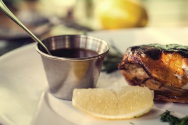 Biberiye, sos ve ahşap arka plan üzerinde limon ile Fırında Balık