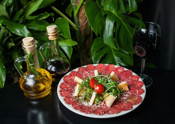 White dish with carpaccio of beef on black table — Stock Photo, Image