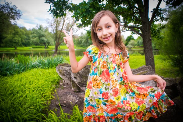 Felice bambina divertendosi i il parco e mostrando segno di pace — Foto Stock