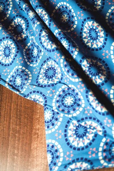 Blått tyg textil med ornament på trä bakgrund — Stockfoto