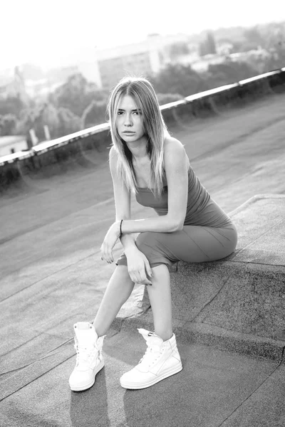 Çatıda mor bir elbise ile beyaz spor ayakkabı giyen güzel genç kadın. Günbatımı — Stok fotoğraf