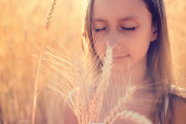 Sıcak bir yaz gününde buğday tarlasında oynayan sevimli küçük kız.