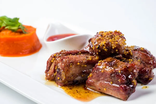 Barbecued pork ribs served with tomato sauce and carrot puree  isolated on white background — Stock Photo, Image