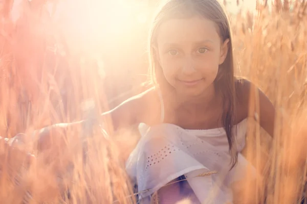 Urocza dziewczynka bawiąca się na polu pszenicy w ciepły letni dzień — Zdjęcie stockowe