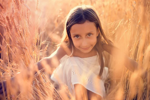 Adorabile bambina che gioca nel campo di grano in una calda giornata estiva — Foto Stock